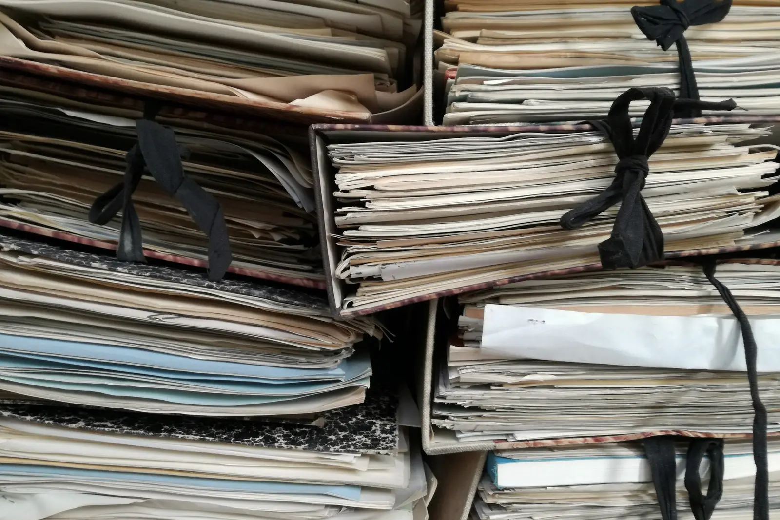 Chemises cartonnées ficelées, empilées et gonflées de documents.