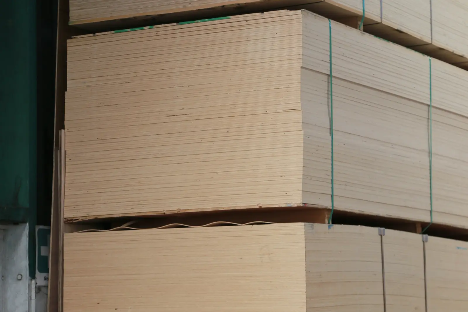Piles de panneaux cerclés stockées à plat sous un auvent, chants tournés vers l’extérieur.