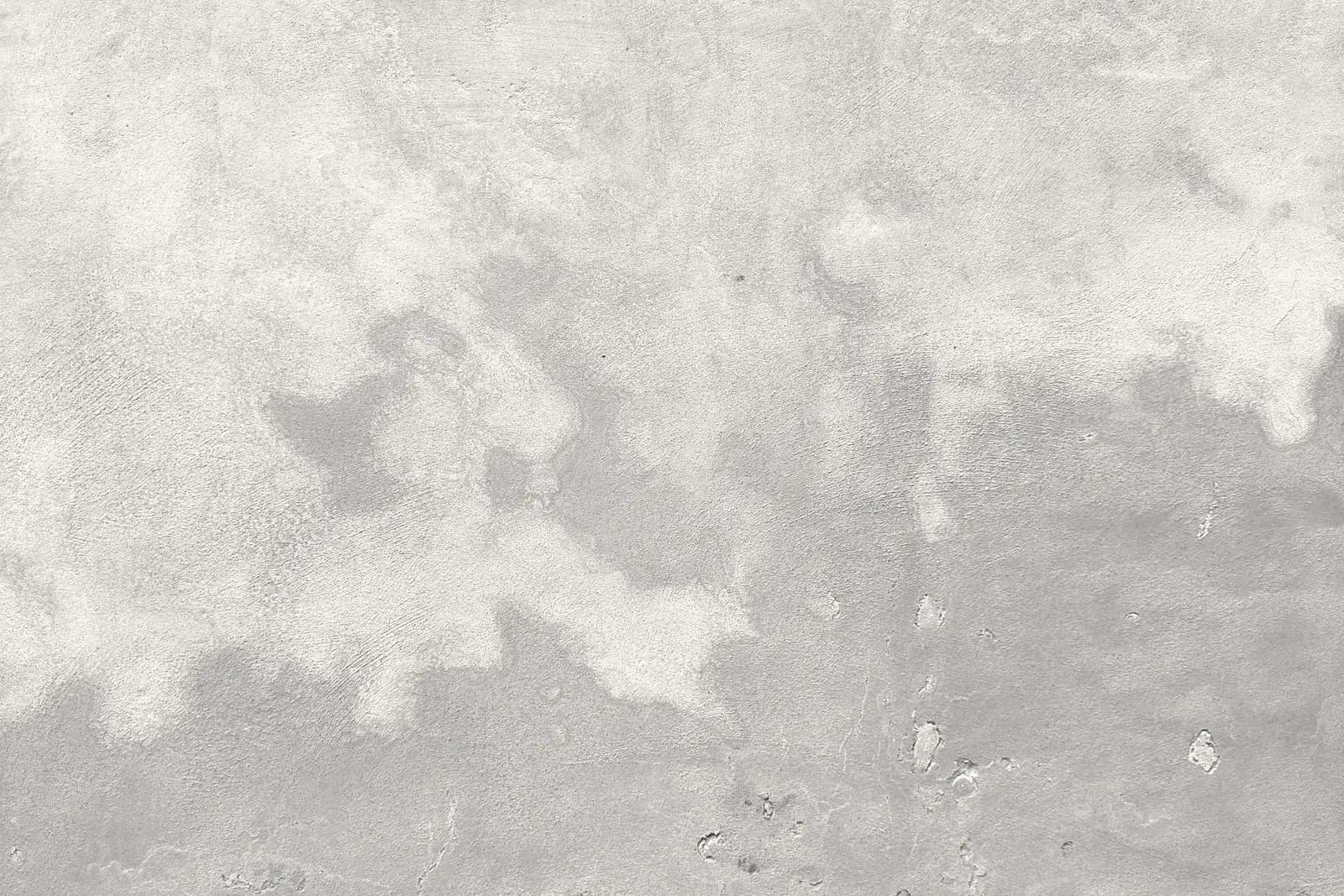 Enduit fraîchement passé sur un mur : les plages déjà sèches ont blanchi, celles qui restent humides sont encore grises.